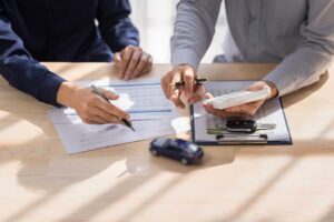 Person reviewing an overdue insurance notice, payment receipt, and policy documents at a kitchen table.