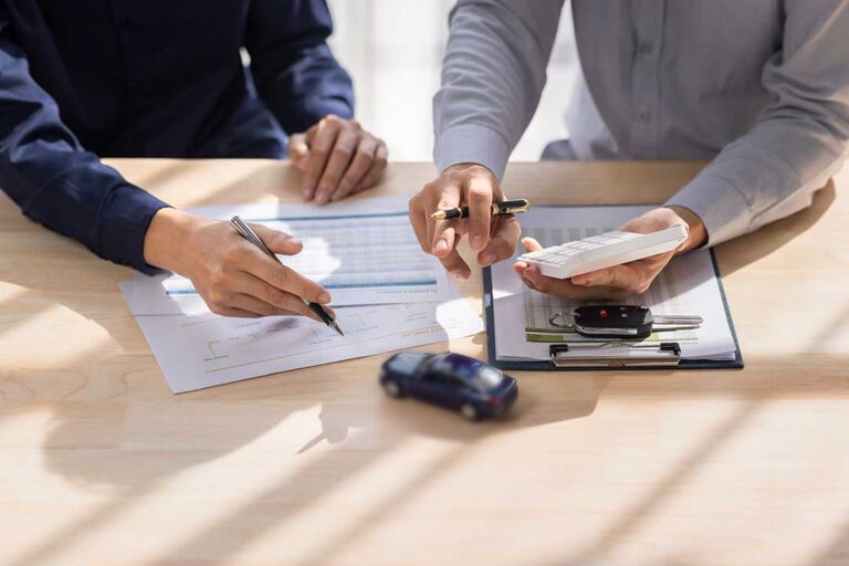Person reviewing an overdue insurance notice, payment receipt, and policy documents at a kitchen table.